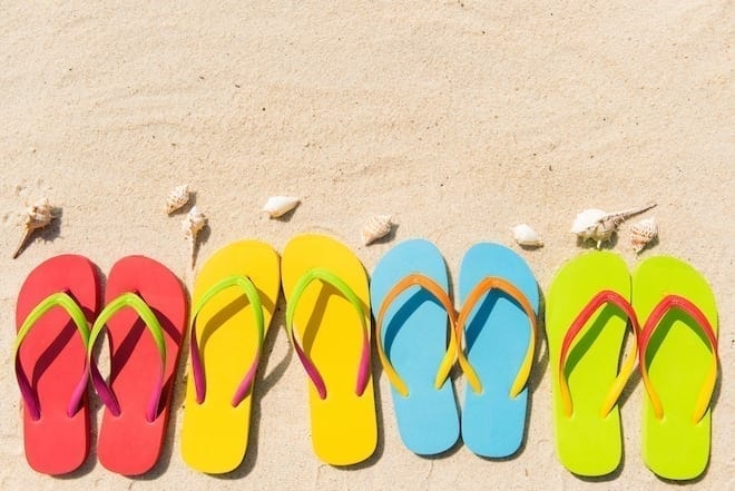 Colorful Derrick Dion flip flops on beach sand